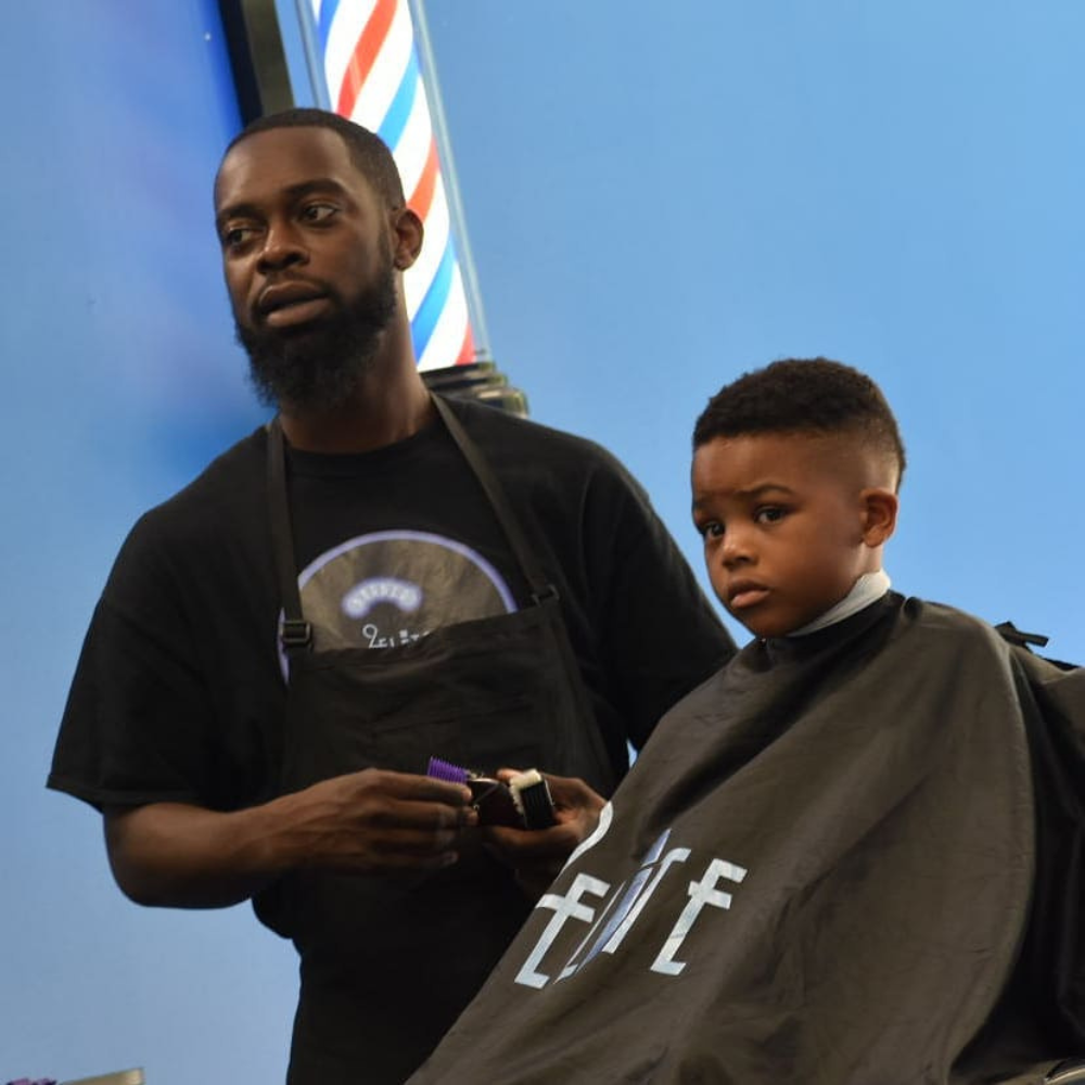 Chris the barber is cutting young boys hair.